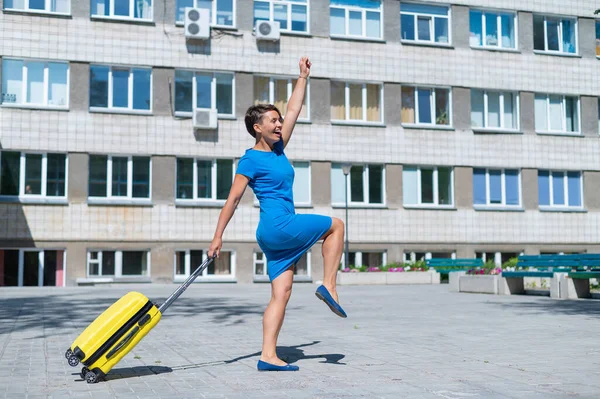 Glückliche Frau läuft mit gelbem Koffer mit Rädern die Straße entlang — Stockfoto