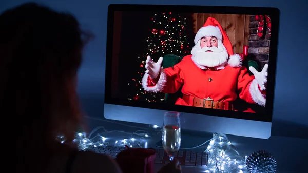 Woman remotely talking with Santa Claus on a video call on your computer. A man dressed as Santa Claus congratulates his girlfriend on Christmas. 2021 new year concept. — Stock Photo, Image