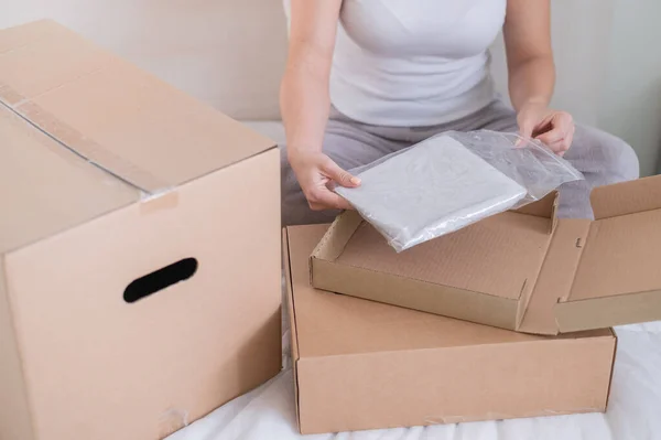 Caucasian woman opens an order while sitting in bed. Online shopping concept with home delivery — Stock Photo, Image