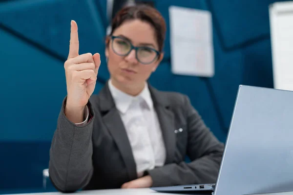 Arga affärskvinna sitter vid sitt skrivbord och pekar finger. — Stockfoto