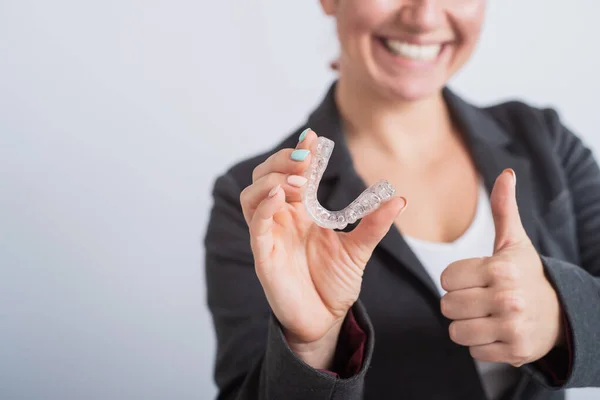 Business woman holding a transparent removable retainer and showing a thumb up — Stock Photo, Image