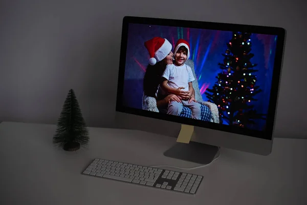 Mère et fils dans santa claus chapeaux félicitent joyeux Noël sur un appel vidéo sur un ordinateur — Photo