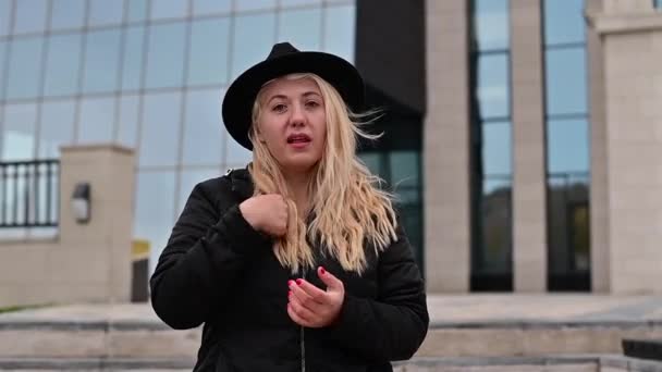 Эмоциональная глухая и тупая блондинка в шляпе говорит на языке жестов. — стоковое видео