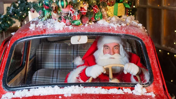 Портрет Санта-Клауса за рулем красной машины и доставки подарков на Рождество — стоковое фото