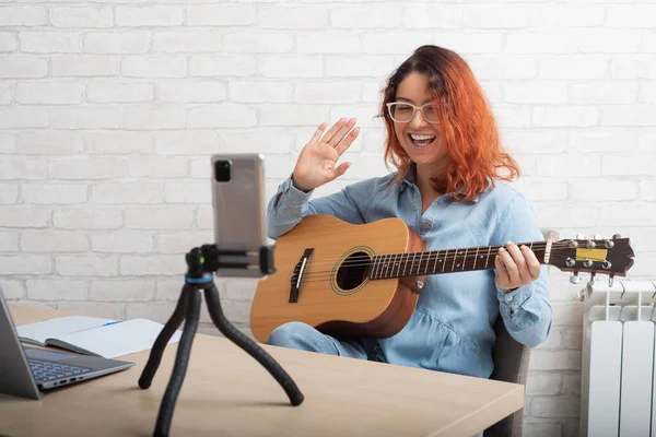 Kaukasierin, die live auf einem Smartphone Gitarre spielt. Das Mädchen führt einen Musikvideoblog — Stockfoto