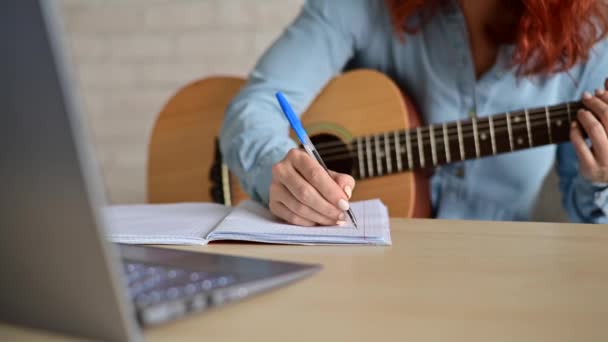 Женщина с гитарой пишет заметки в блокноте. Девушка сочиняет песню — стоковое видео