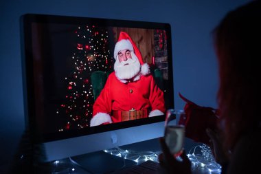 Noel Baba 'yla yeni yıl arifesinde bilgisayar başında konuşan bir kadın..