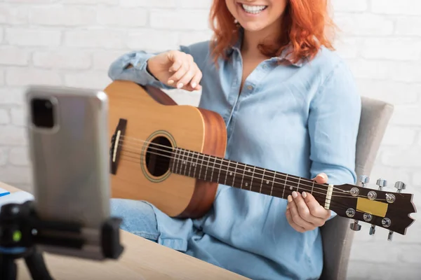 Blanke vrouw speelt gitaar live op een smartphone. Het meisje leidt een muziek video blog — Stockfoto