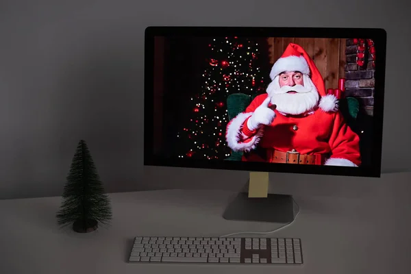 Papai Noel deseja remotamente Feliz Natal através de uma chamada de vídeo no computador. Um homem vestido de Pai Natal num monitor. 2021 conceito de ano novo — Fotografia de Stock