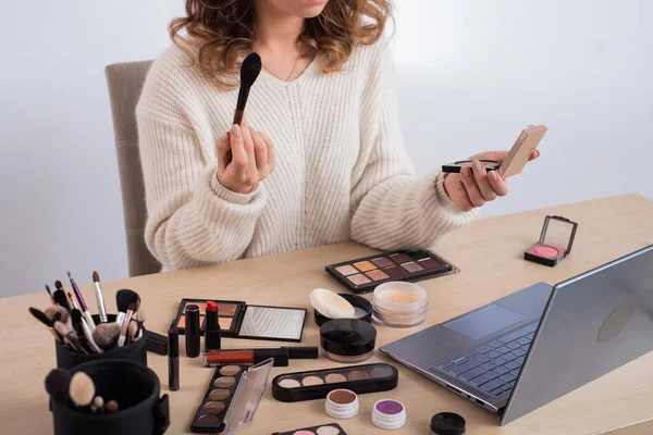 Uma mulher sem rosto assiste ao treinamento on-line de um artista de maquiagem profissional em um laptop. Ensino à distância — Fotografia de Stock