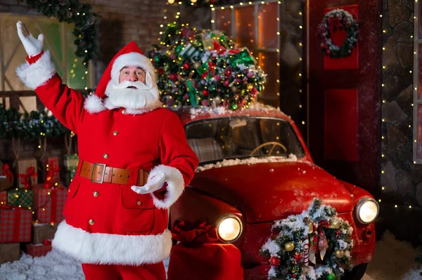 Papai Noel posa perto de um carro clássico vermelho. Feliz Natal! — Fotografia de Stock