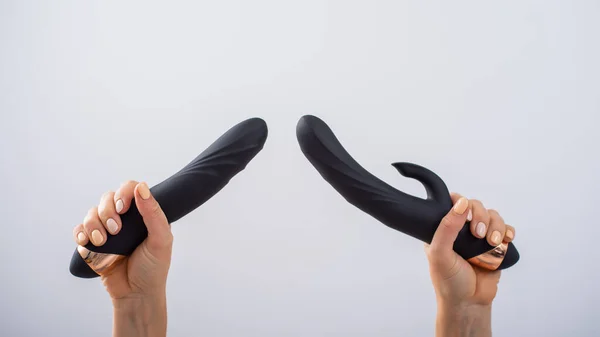 O femeie fără chip deține două dildo-uri negre pe un fundal alb — Fotografie, imagine de stoc