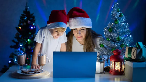 Joyeux maman et fils parlant sur un appel vidéo sur un ordinateur portable le soir de Noël. — Photo