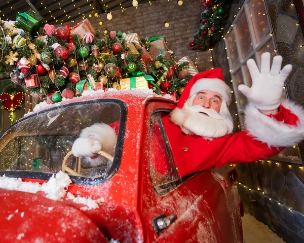 Santa Claus cumprimentando enquanto dirige um carro retro vermelho. Feliz Natal! — Fotografia de Stock