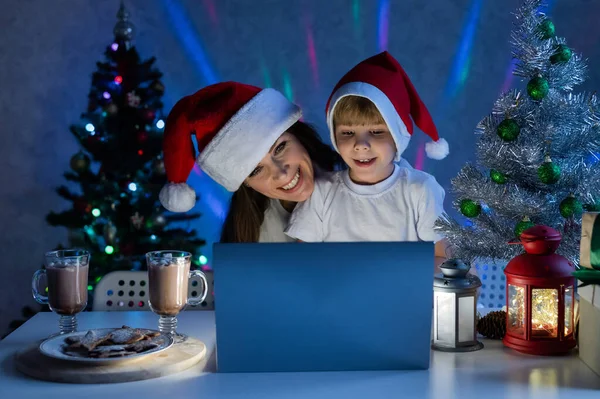 Joyeux maman et fils parlant sur un appel vidéo sur un ordinateur portable le soir de Noël. — Photo