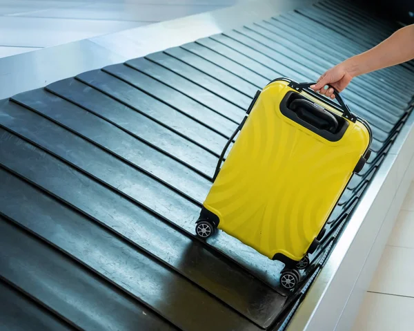Una mujer toma una maleta del carrusel de equipaje. —  Fotos de Stock