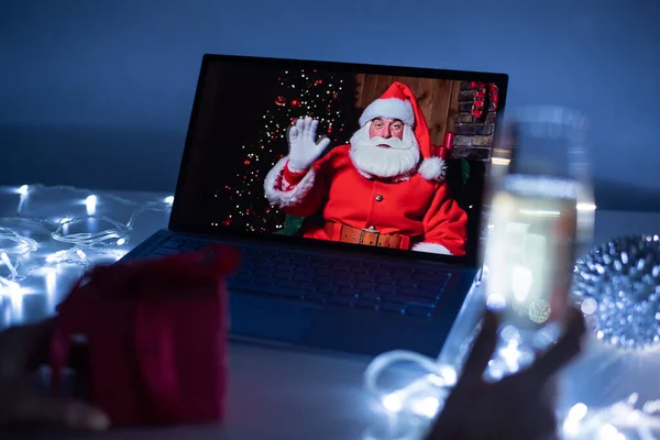 Uma mulher está comemorando remotamente a noite de Natal e se comunicando com o Papai Noel via vídeo em um laptop — Fotografia de Stock