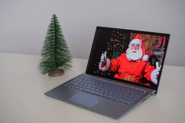 Papai Noel deseja Feliz Natal por videochamada em um laptop. Comunicação remota — Fotografia de Stock