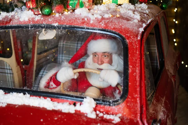 Retrato de Papai Noel dirigindo um carro vermelho e entregando presentes para o Natal — Fotografia de Stock