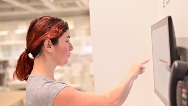 Woman looking for information with a digital touch screen in a store — Stock Video