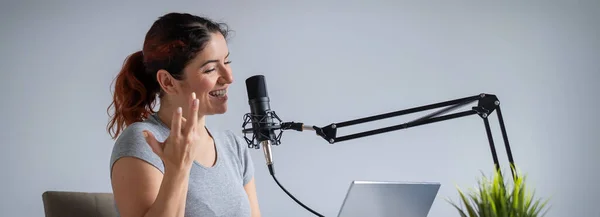 Una encantadora mujer presentadora de radio está transmitiendo en vivo en un portátil. Concepto de radio en línea. Pantalla ancha —  Fotos de Stock