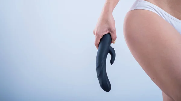 A faceless woman in white cotton panties holds a black dildo against a white background. Female vibrator for masturbation. Empty space — Fotografia de Stock