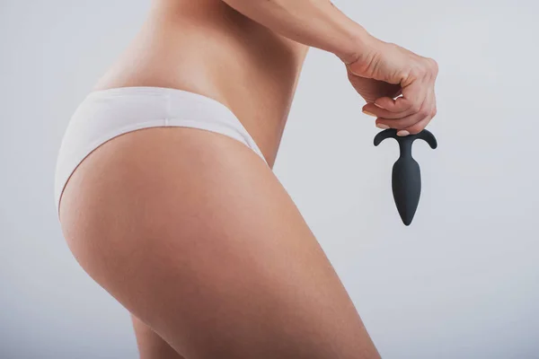A faceless woman in white cotton panties holds a black butt plug on a white background — Stok fotoğraf