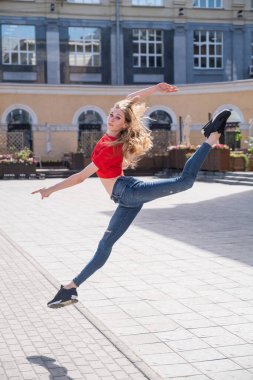 Güzel ince dansçı dışarı zıplıyor. Sokakta poz veren genç bir kadın.