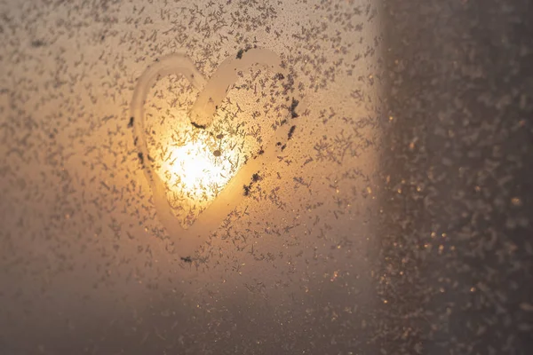 A heart drawn on a frozen winter window at sunset. — Stock Photo, Image