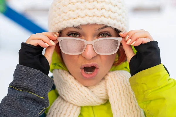 Кавказская женщина в очках улыбается и замерзает на улице зимой. — стоковое фото