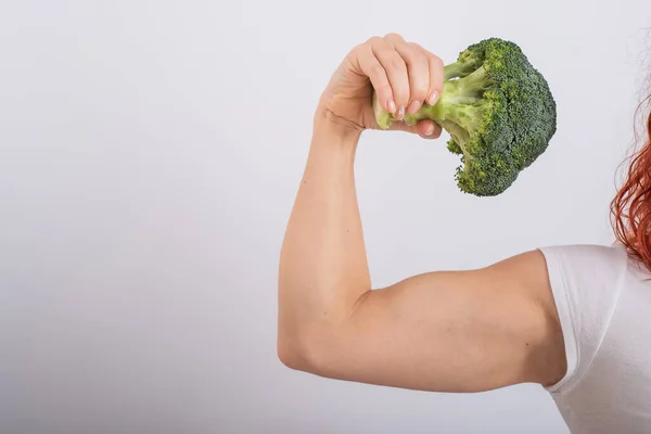 Muskulöse Frau mit Brokkoli in der Hand. Weiblicher Bizeps — Stockfoto