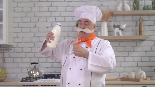 Vriendelijke oudere melkboer giet melk uit een fles in een glas. — Stockvideo