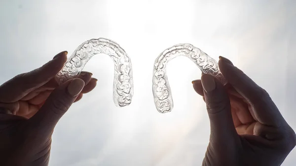 Bandejas transparentes para corrigir dentes em mãos femininas. Retentores de plástico removíveis — Fotografia de Stock