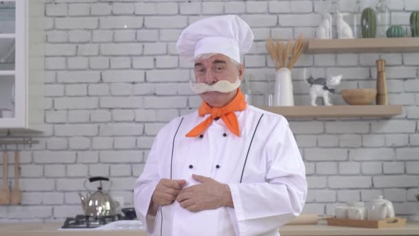 Portret van een oudere mannelijke chef met bossige grijze snor in de keuken. — Stockvideo
