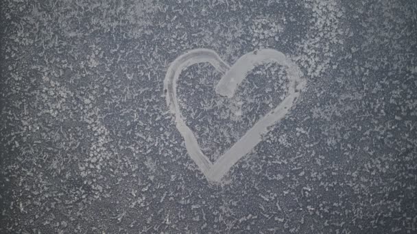 Un cœur dessiné sur une fenêtre d'hiver gelée au coucher du soleil. — Video
