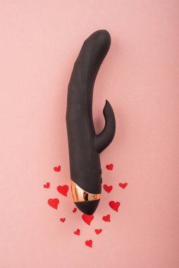 Black clitoral vaginal dildo and hearts on a pink background. Female vibrator as a gift for Valentines Day