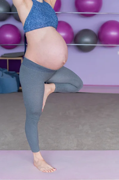 Oříznutý pohled na nerozpoznatelnou těhotnou ženu ve třídě jógy. Budoucí matka bez tváře s holým bříškem se věnuje fitness. Pozice stromu. — Stock fotografie