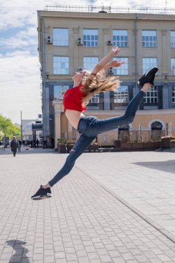 Güzel ince dansçı dışarı zıplıyor. Sokakta poz veren genç bir kadın.