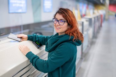 Havaalanındaki gişede bir kadın uçuş bileti almak için pasaportunu veriyor.