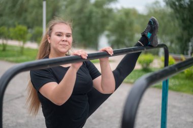 Şişman kız oyun parkındaki dengesiz parmaklıkların üzerinde gerinmekle meşgul. Kilo vermek için spor yapan güzel, genç, güler yüzlü bir kadın..