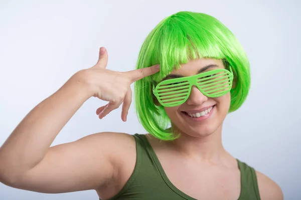 Giovane donna allegra in parrucca verde e occhiali divertenti che celebrano giorno st patricks su uno sfondo bianco — Foto Stock