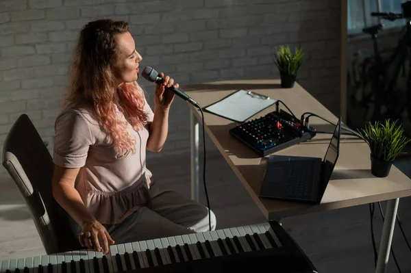 Ausdrucksstarke Sängerin hat einen Videoblog auf einem Laptop. Porträt eines Mädchens, das einen Song mit einer Webkamera aufnimmt und auf einem Synthesizer komponiert. Online-Musikunterricht. Fernstudium in Quarantäne. — Stockfoto