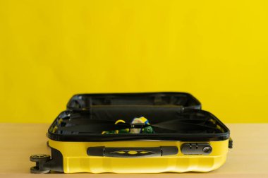 Sarı arka planda bikinili sarı bavul. Bir kadın denize tatile gidiyor.