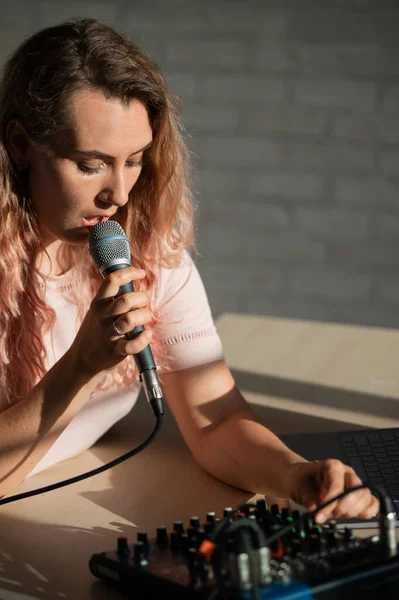 Egy nő mikrofonba énekel és online játszik. Egy női blogger felvesz egy dalt egy szintetizátorral egy laptoppal.. — Stock Fotó
