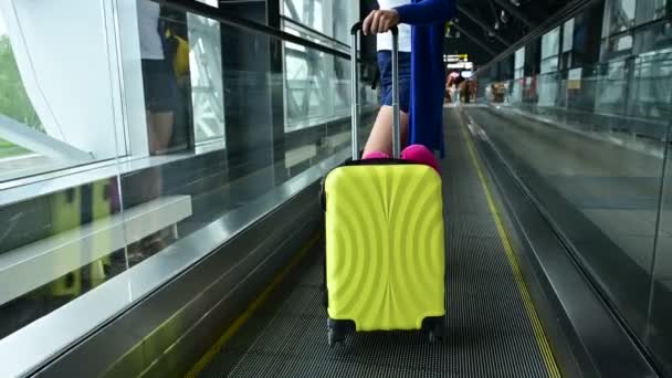 Kaukasierin auf einer waagerechten Rolltreppe mit einem Koffer am Flughafen. Ein Mädchen mit rosa Gepäck fährt auf einem fahrenden Bürgersteig — Stockvideo