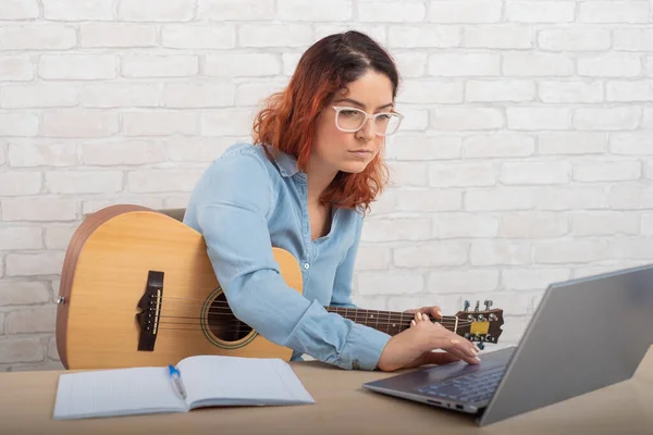 Eine Frau lernt gerade, online Gitarre zu spielen. Musikstunde aus der Ferne — Stockfoto