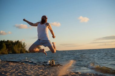Sahilde poz veren acımasız bir adam. Çekici bir kızın parodisi..