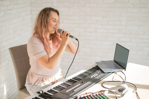 Eine Frau singt in ein Mikrofon und dreht einen Videoblog auf einem Laptop — Stockfoto