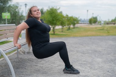 Dışarıdaki banktan şınav çeken genç şişman kadın. Tombul kız spor yapıyor..
