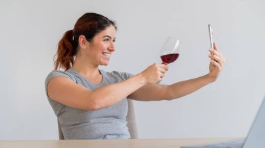 Beyaz bir kadın kırmızı şarap içer ve arkadaşlarıyla akıllı telefondan iletişim kurar. Karantinaya alınan kız, bayramı online bir konferans aracılığıyla kutluyor.